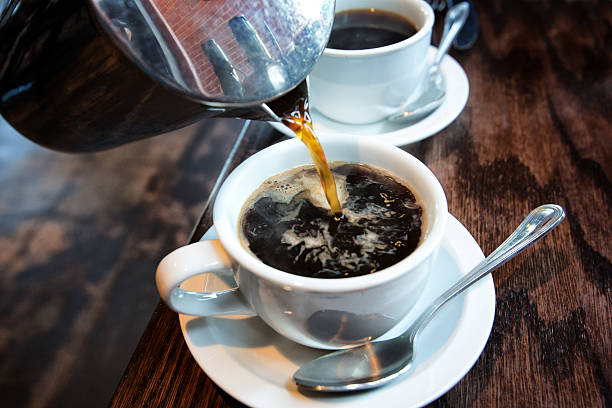 Hot Coffee from a French Press Fresh hot coffee being poured into a cup from a stainless steel french press in a trendy cafe cup stock pictures, royalty-free photos & images