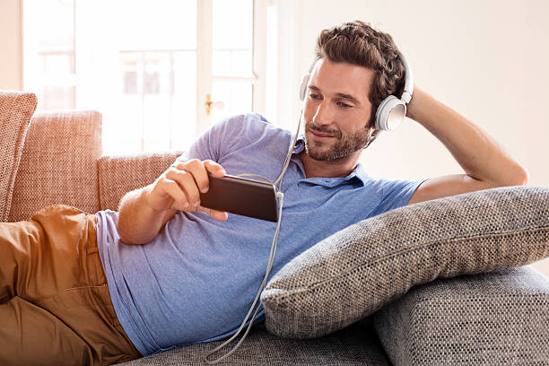 Man at home watches a movie on cell phone stock photo