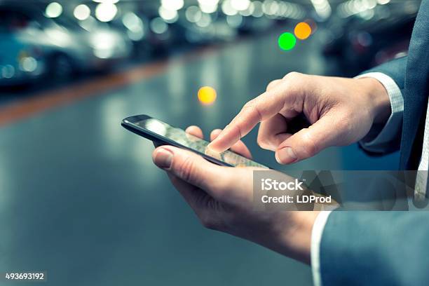 In Parking Lot A Man Using Mobile Phone Light Bokeh Stock Photo - Download Image Now