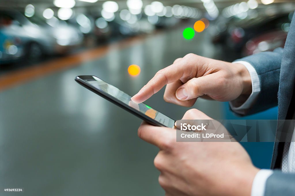 In parking lot a man using mobile phone. Light bokeh Male smartphone app car park Vintage filter Mobile Phone Stock Photo