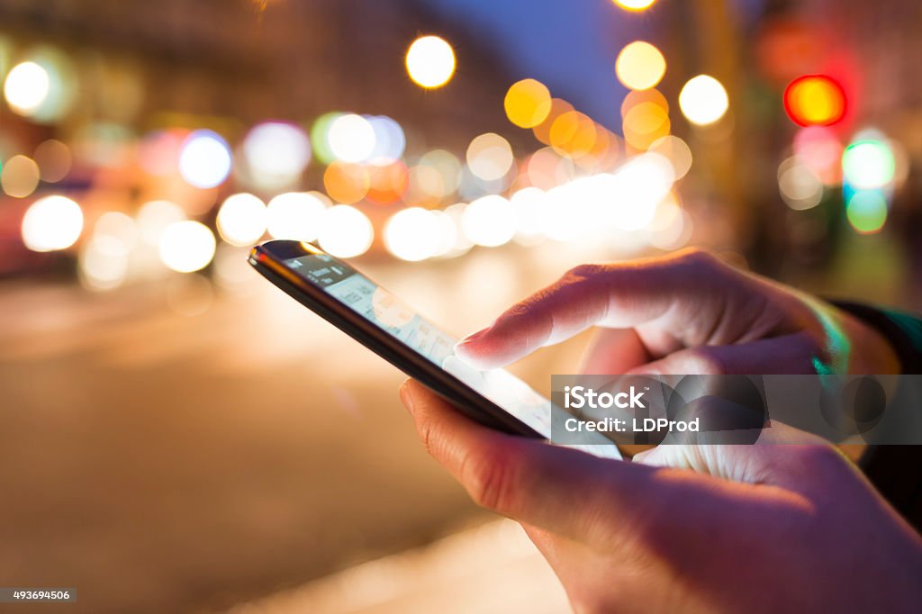 Man using his Mobile Phone in the street, bokeh close up of male hands nightlight smartphone Mobile Phone Stock Photo