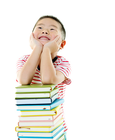 Asian boy with stack of books against white background.