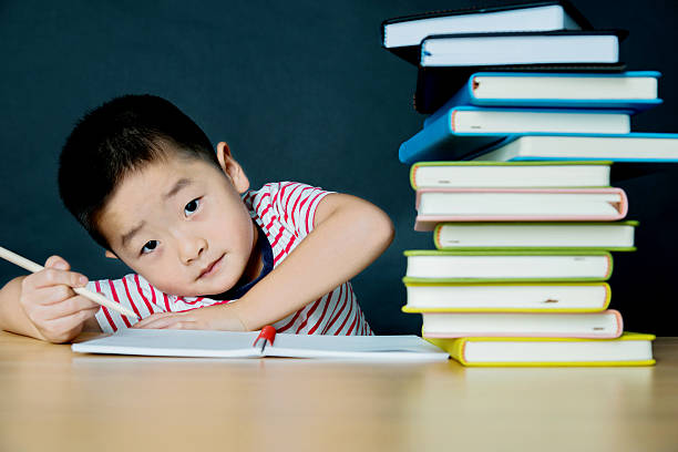 wenig asiatische junge mit stapel von büchern - reading and writing little boys reading asian ethnicity stock-fotos und bilder