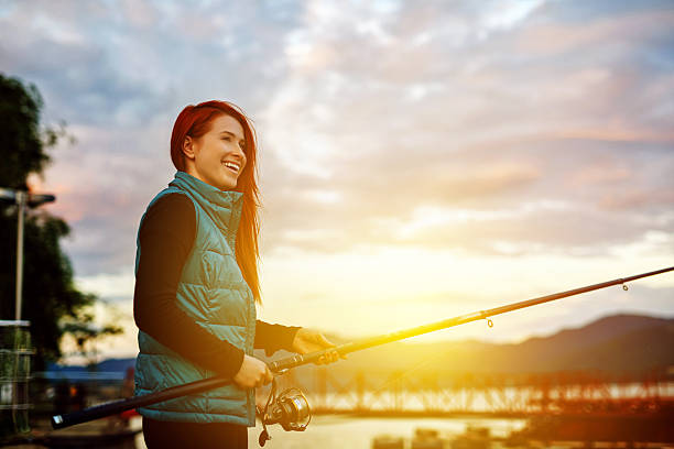 photo of relaxed and happy woman with fishing hook looking away and smiling, enjoying fishing day.
