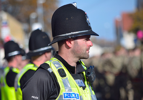 St Neots, Cambridgeshire, England - October 20, 2015: British Police on duty in numbers at a military parade in St Neots Cambridgeshire all wearing high vis jackets and helmets.