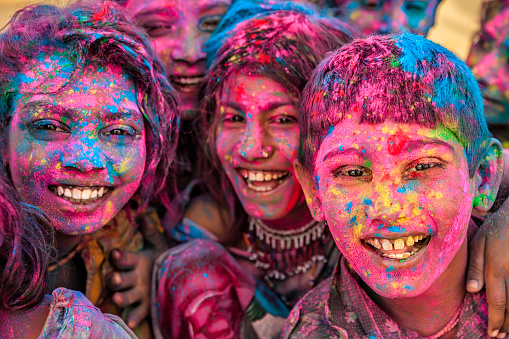 Group of happy Gypsy Indian children playing happy holi on sand dunes in desert village, Thar Desert, Rajasthan, India. Holi is a religious festival in India, celebrated, with the color powders, during the spring.
