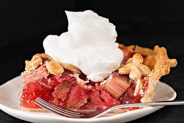 Slice Of Rhubarb Pie With Cream An extreme close up shot of a slice of strawberry rhubarb pies topped with whipped cream. rhubarb photos stock pictures, royalty-free photos & images