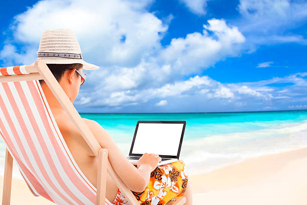 istock relaxed man sitting on beach chairs and using a laptop. 493705405