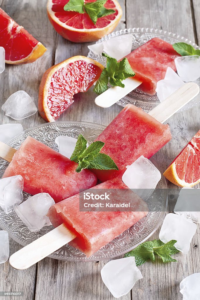 Red grapefruit popsicles Red grapefruit homemade popsicles with ice cubes. Selective focus. Flavored Ice Stock Photo