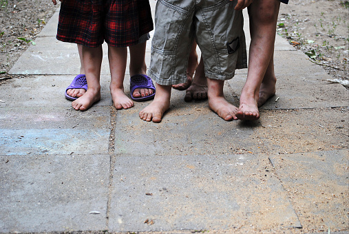 Homeless children with bare feet standing on a stone path.
