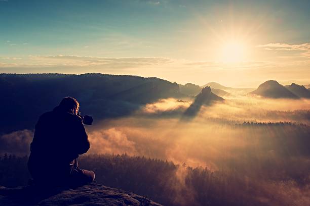 istock Professional photographer silhouette above a clouds sea, misty mountains 493713298