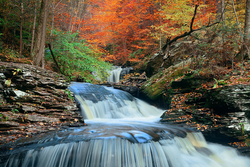 Autumn waterfalls in park with colorful foliage.