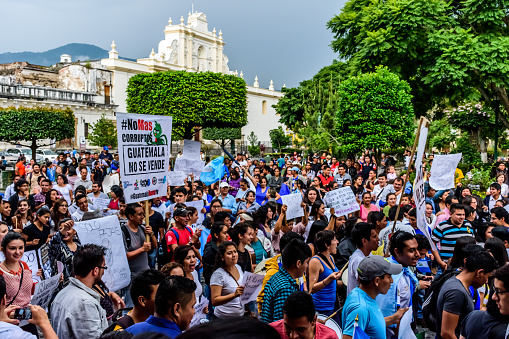 Antigua, Guatemala - August 27, 2015: Locals wave Guatemalan flags & slogans protesting against government corruption & demanding resignation of President Otto Perez Molina in front of city hall.  Sign reads \