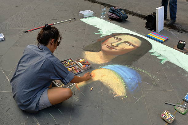 Artist paints face of a Mona Lisa in Florence, Italy Florence, Italy - August 19, 2015: The artist paints a picture (face of a Mona Lisa) of colored chalk on the sidewalk mona lisa photography stock pictures, royalty-free photos & images