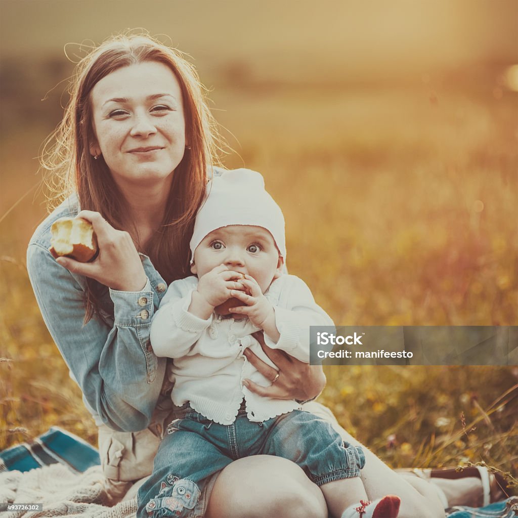 Happy young mom with lovely daughter. Young happy mother and lovely daughter have fun with apples at countryside during sunset. 2015 Stock Photo