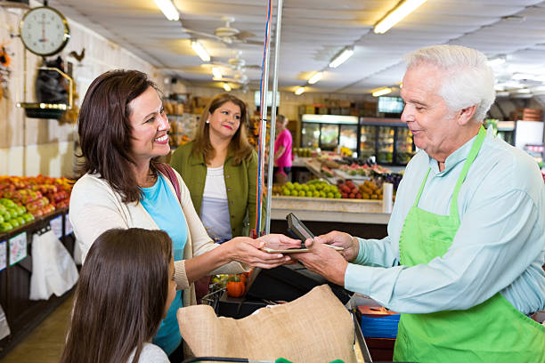 istock Senior grocery store owner accepting payment with digital tablet 493733728