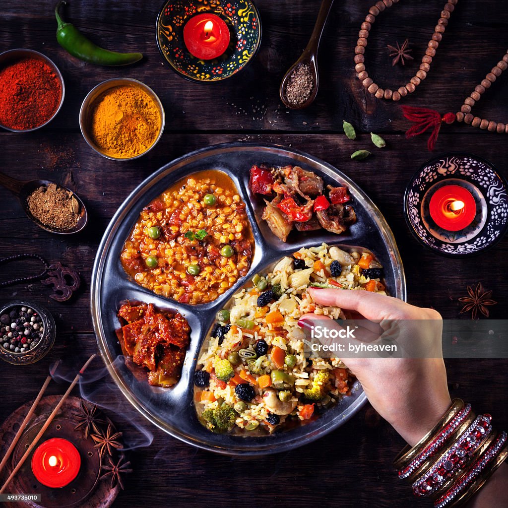 Diwali celebration food Woman eating vegetarian biryani by her hand with bangles near candles, incense and religious symbols at Diwali celebration Eating Stock Photo