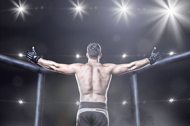 istock mma fighter in arena celebrating win, behind view 493736026