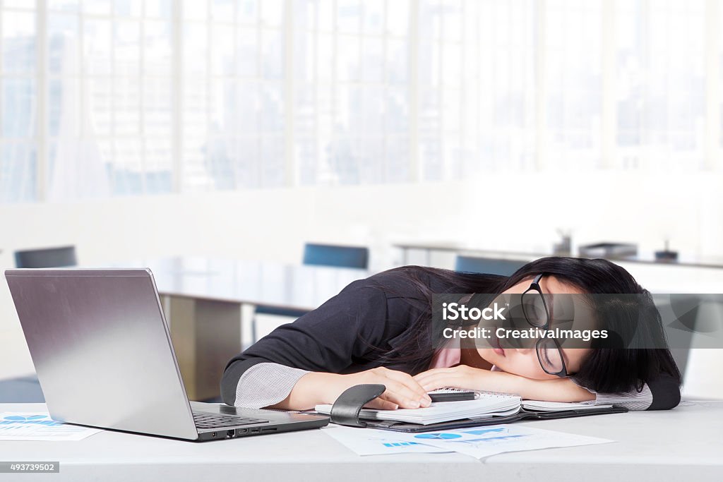 Exhausted female entrepreneur napping in office Portrait of female worker wearing formal suit relaxing and sleeping in office with laptop in office 2015 Stock Photo