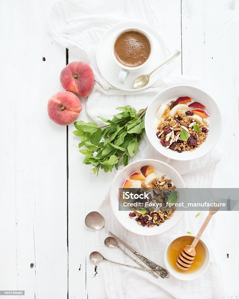 Healthy breakfast. Bowl of oat granola with yogurt, fresh fruit Healthy breakfast. Bowl of oat granola with yogurt, fresh fruit, mint and honey. Cup of coffee, vintage silverware. Top view, copy space Backgrounds Stock Photo