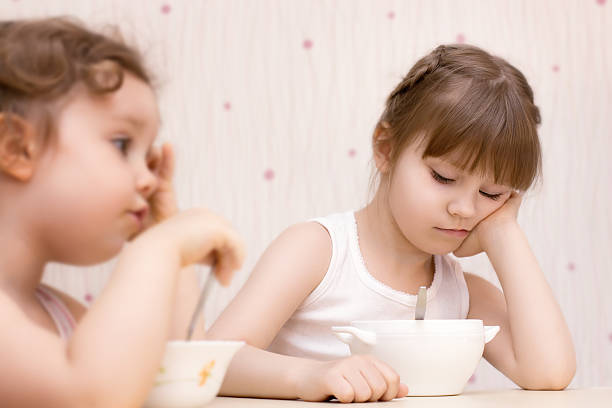 istock Two pretty little girls eating without appetite 493742390