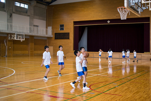 Japanese children practising basketball in the school gymnasium.