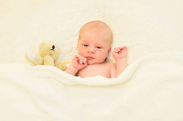 istock Cute baby sleeping together with teddy bear toy on bed 493743882
