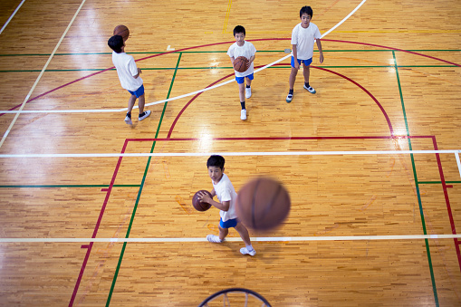 Japanese boys playing basketball in the school gymnasium.