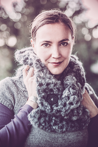 Beautiful Young woman wearing handmade woolen crotcheted scarf. Vertical outdoors image.