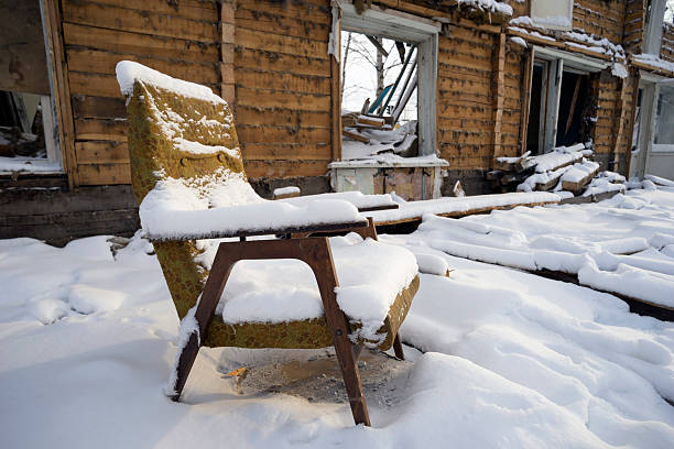 Old chair covered with snow in a ruined house .