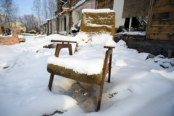 Old chair covered with snow in a ruined house .