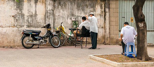 Naina Devi, Himachal Pradesh, India - March 2022: Male barber performing the hair cut to his client at his shop.