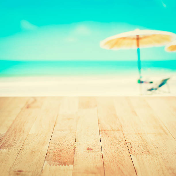 istock Wood table top on blurred white sand beach background 493746612