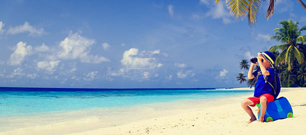 istock little boy travel on summer tropical beach with suitcase 493747260