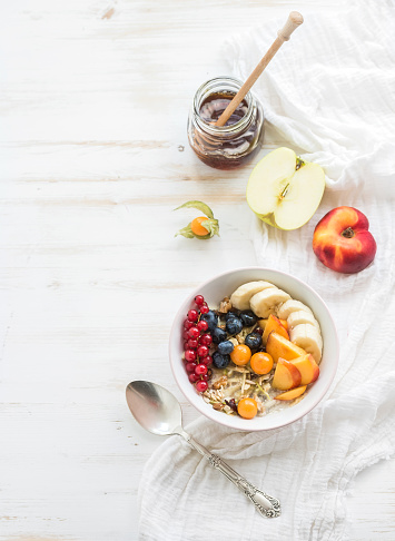 Healthy breakfast. Bowl of oat granola with yogurt, fresh berries, fruit and honey. Top view, copy space