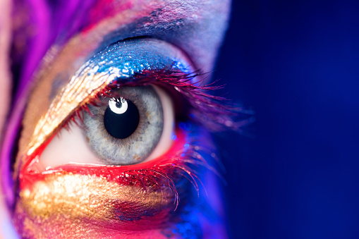 Closeup image of woman eye with creative makeup painted different colors