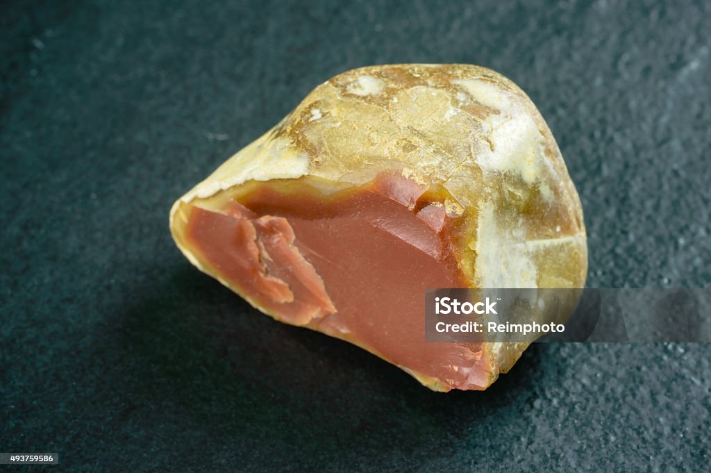 Flint Lovely brown flint stone with lighter colored outer layer. Shallow focus on closest edge. Black stone background. 2015 Stock Photo