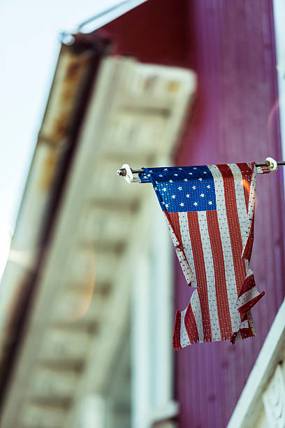 istock Proud but torn American Flag hanging from building. 493761978
