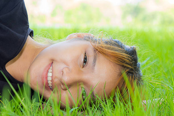 Portrait young women horizontal on grass with her face closeup