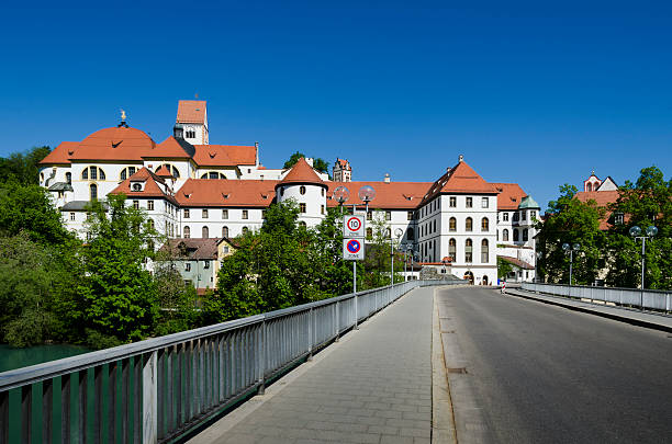 St Mang Abbey and Basilica, Lech River, Fussen, Bavaria, Germany St Mang's Basilica and St Mang's Abbey on the Lech River, Fuessen, Bavaria, Germany. Benedictine monastery. Bridge over River Lech. st mang stock pictures, royalty-free photos & images