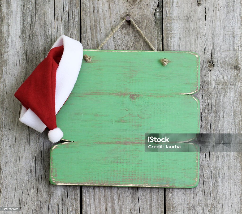 Blank sign with Santa Claus hat Blank green wood sign with Christmas Santa Claus hat hanging on antique rustic wooden background Christmas Stock Photo