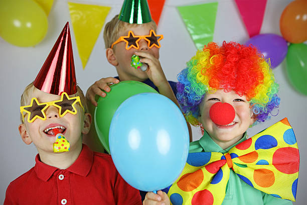 Group of children sitting at the table and eating cupcakes and sweets on a indoors Birthday party