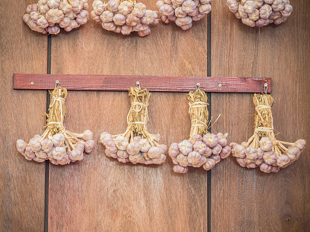 cadeia de alho pendurado na parede de madeira - garlic hanging string vegetable imagens e fotografias de stock