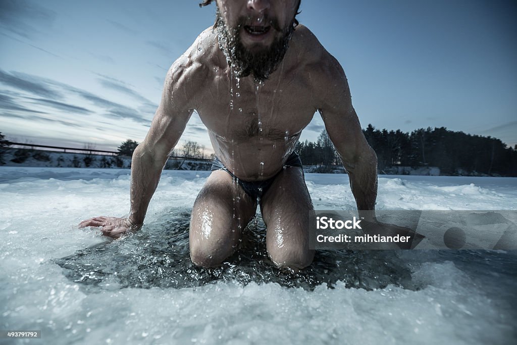 Ice hole Young man bathing in the ice hole Cold Temperature Stock Photo