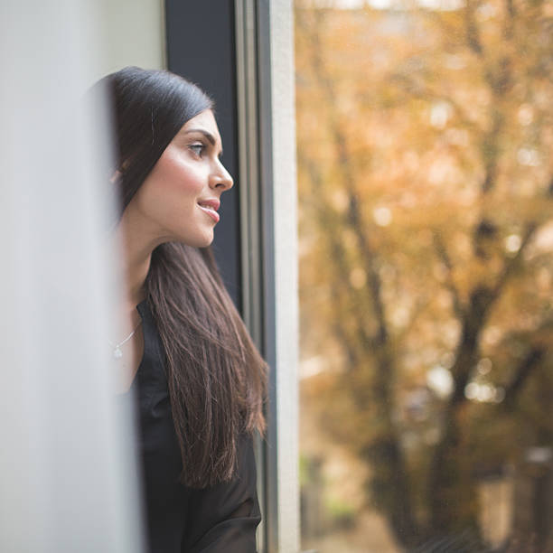istock Beautiful Young Woman Looking Out of Window 493793708