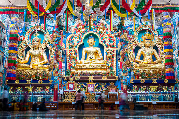 The Golden Temple of the Namdroling Nyingmapa Monastery Bylakuppe, Karnataka, India - January 9, 2015: 18 meters high statues inside the Golden Temple - Padmasmbhava, the Buddha and Amitayus. Visitors and tourists moving in and out of the Namdroling Nyingmapa Monastery. dalai lama stock pictures, royalty-free photos & images