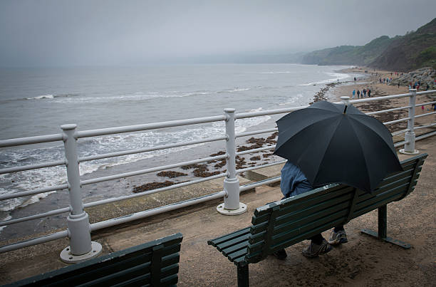 a couple sat on bench looking out to sea at Robin Hoods Bay