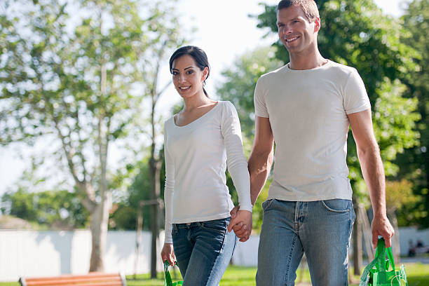 Cute teenage couple holding hands and walking in public park together.