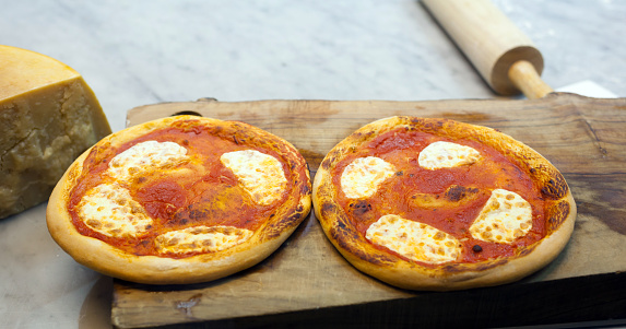 Two small pizza margherita on wood cutting board