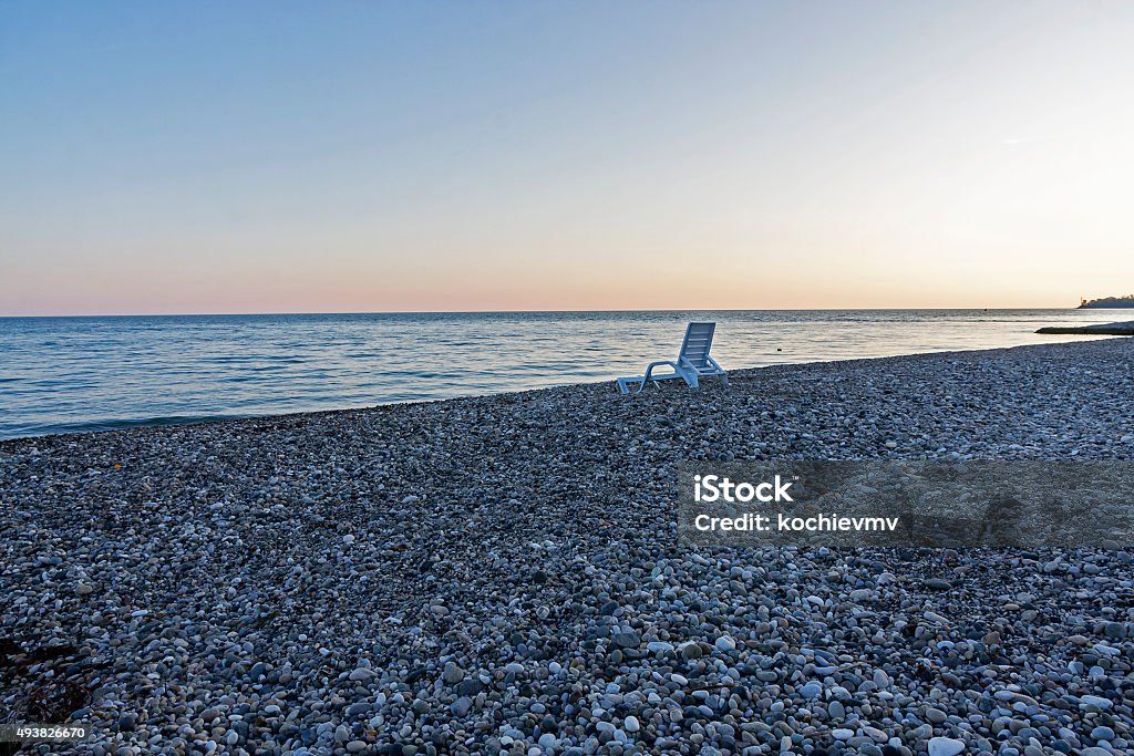 Cama solar en pebbly beach cerca del mar al atardecer - Foto de stock de 2015 libre de derechos